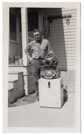 <h5>Clinton Stillman</h5><p>Clinton Stillman posing in front of old diving suit.  Photo provided by family of Ivo Schommer.</p>